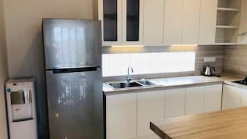 A modern kitchen with a stainless steel refrigerator, a water dispenser, a sink, and wooden countertops.