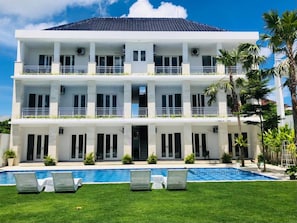 Um edifício de vários andares com piscina e espreguiçadeiras.