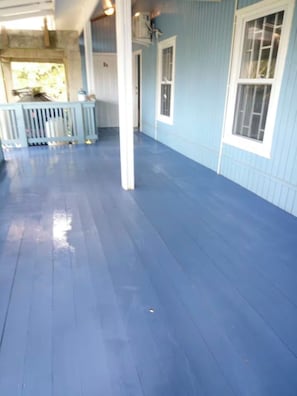A covered porch with a blue floor, white columns, and a view of the outdoors. - Tranquil 2-bedroom apartment with AC in charming Pensacola (Roatan)