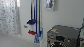 A room with a washing machine, a first aid kit, and cleaning supplies.