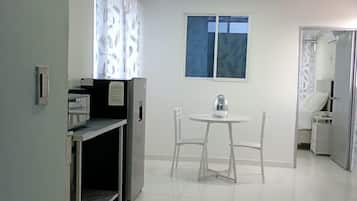 A clean, modern kitchen with a dining area, a window, and a door leading to another room.