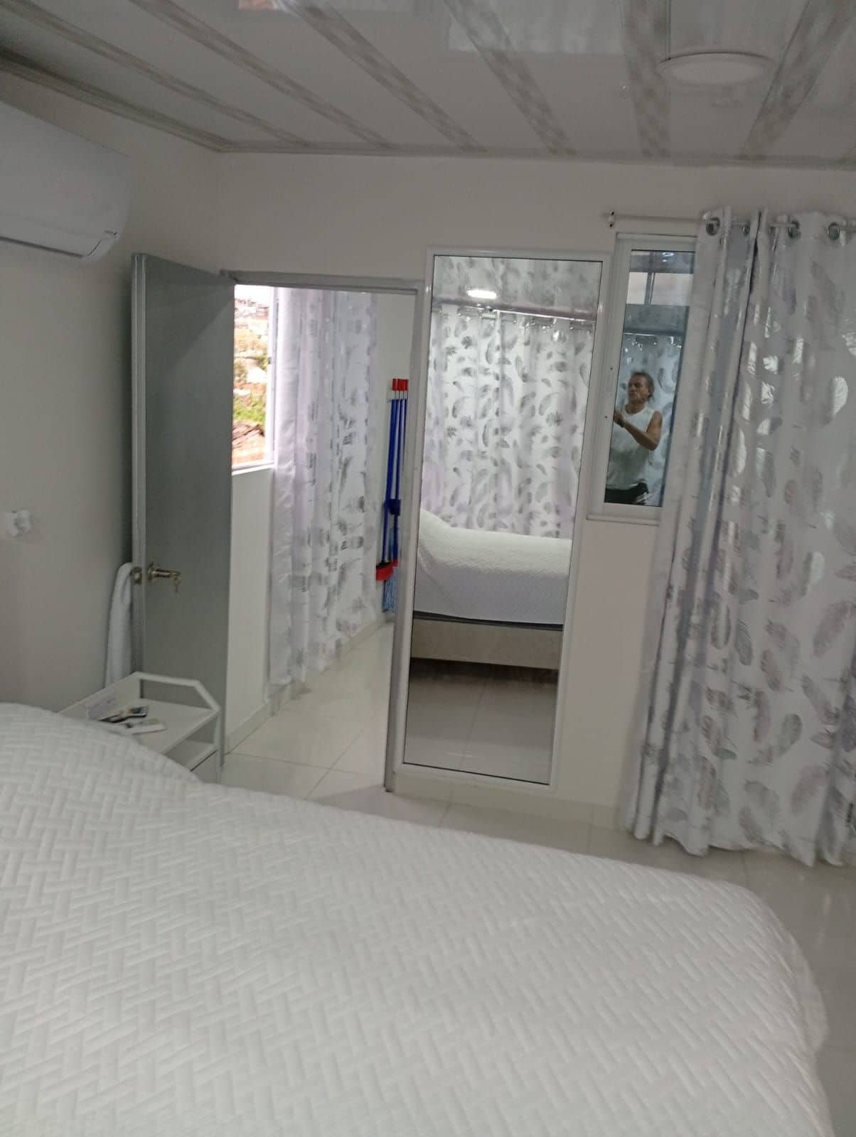 A bedroom with a bed, a mirror, and a bathroom visible through an open door.