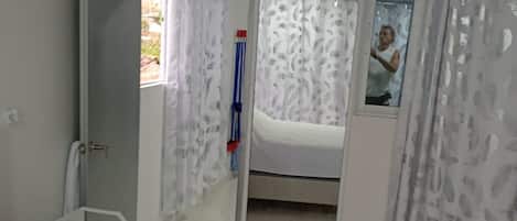 Un dormitorio con cama, un espejo y un baño visible a través de una puerta abierta.