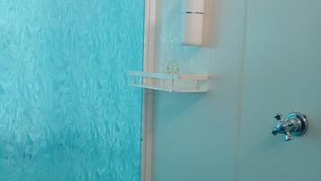 A bathroom with a frosted glass door, a white towel dispenser, and a metal faucet.