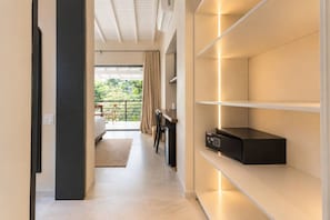 Una habitación de hotel moderna con cama, escritorio y vistas a la vegetación exterior.