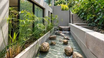 A modern outdoor space with a water feature, stone steps, and lush greenery.
