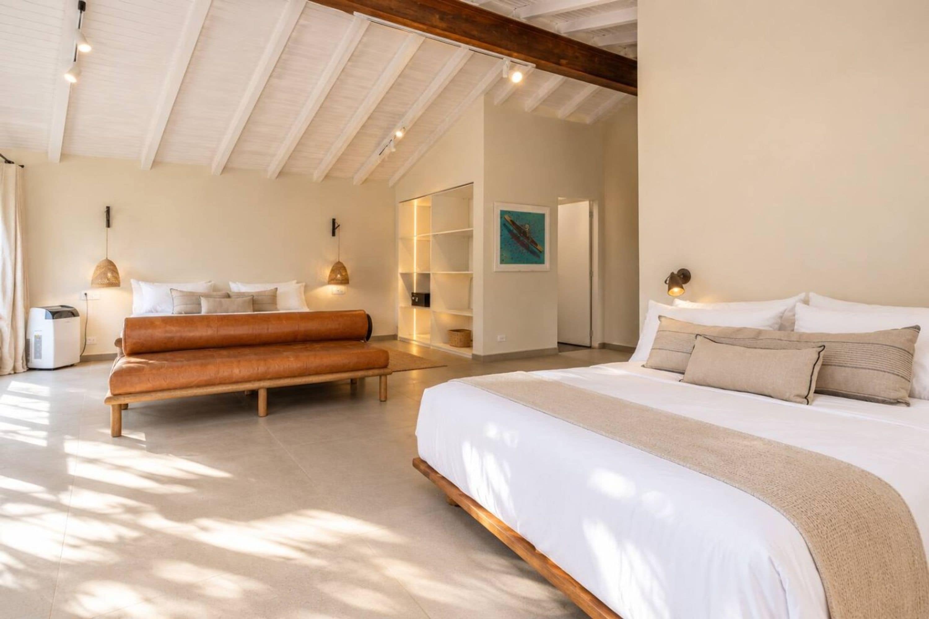 A spacious bedroom with a large bed, a bench, and a built-in bench seating area.