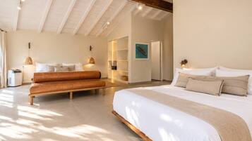 A spacious bedroom with a large bed, a bench, and a built-in bench seating area.