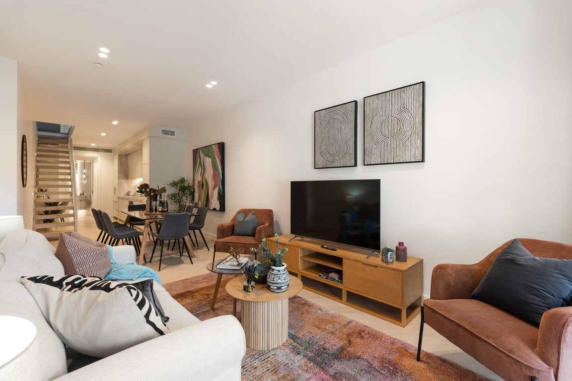A modern living room with a sofa, a coffee table, a TV, and artwork on the wall.