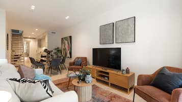 A modern living room with a sofa, a coffee table, a TV, and artwork on the wall.
