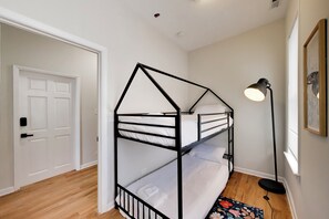 A bunk bed with a geometric design, a door with a handle, a floor lamp, and a window with blinds. - The Grandstand - Modern 4Br 3Ba Penthouse near Sox Stadium (Chicago)