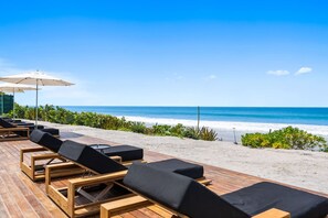 A beachside lounge area with wooden loungers and umbrellas, overlooking the ocean. - Naya 6201 Tower VI in Punta de Mita (Punta de Mita)