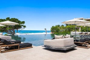 A poolside area with lounge chairs, umbrellas, and a view of the ocean. - Naya 6201 Tower VI in Punta de Mita (Punta de Mita)