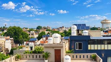 Área residencial com vários edifícios, alguns com painéis solares e reservatórios de água, sob um céu azul claro.