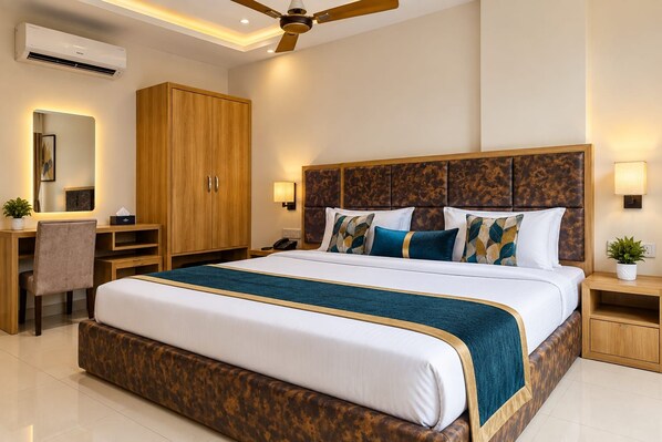A hotel room with a large bed, a desk, a wardrobe, a ceiling fan, and a nightstand with a lamp. - Hotel Sulit Agra Near Taj Mahal  (Agra)