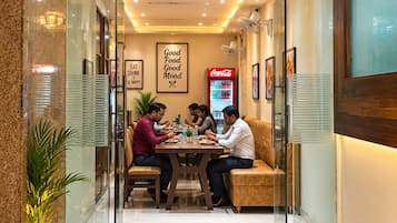 Restaurante com uma placa vermelha listando pratos como Idli, Chowmein e Pizza.