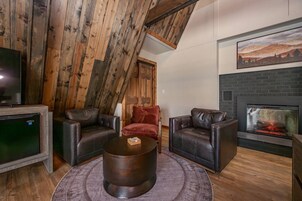 Una sala de estar acogedora con chimenea, sofás de cuero, una mesa de centro y un televisor.