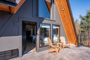 Un edificio moderno con techo inclinado, ventanas grandes y un patio con mobiliario exterior.