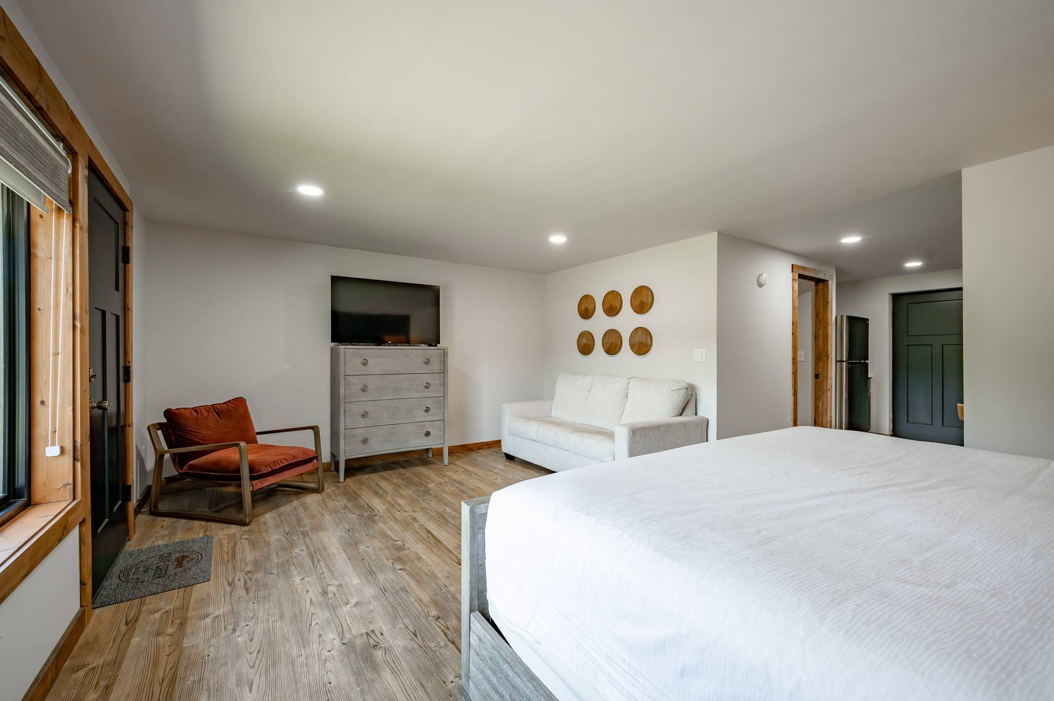 Un dormitorio con cama, cómoda, televisor, sofá y sillón.