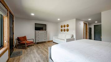 Un dormitorio con cama, cómoda, televisor, sofá y sillón.
