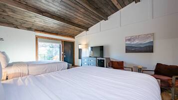 Un dormitorio con dos camas, televisión, un cuadro y techo de madera.