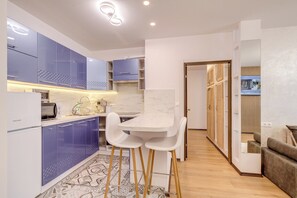 Una cocina moderna con armarios azules, una encimera blanca y un comedor con mesa y sillas.