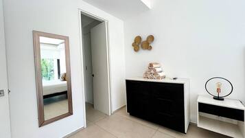 A modern room with a large mirror, a black and white dresser, and a wall-mounted light fixture.