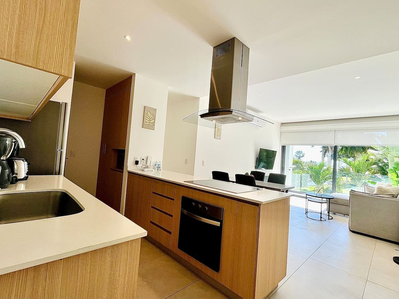 A modern kitchen with a central island, built-in oven, and a stainless steel range hood.