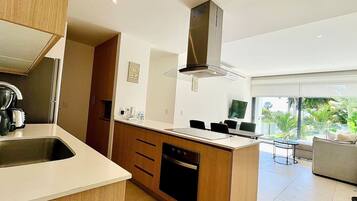 A modern kitchen with a central island, built-in oven, and a stainless steel range hood.