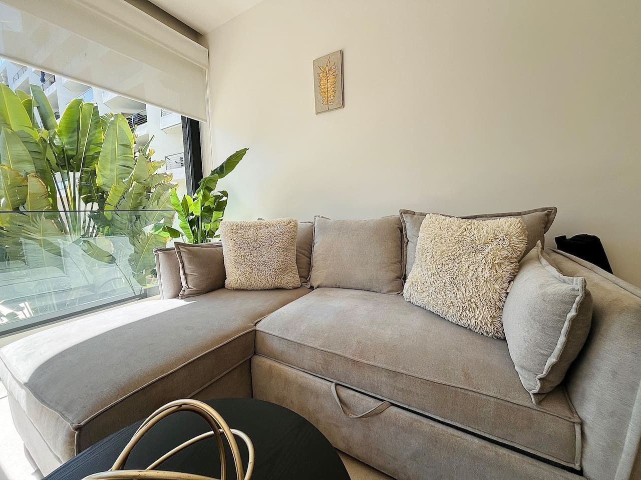 A modern living room with a sectional sofa, a small round table, and a potted plant.