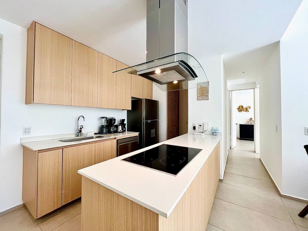 Une cuisine moderne avec des meubles en bois, un îlot central et une hotte de cuisine en acier inoxydable.