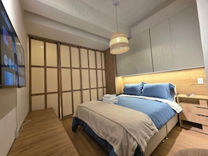 A modern bedroom with a bed, bedside tables, and a hanging light fixture. - North Point Hills 2 (Bogotá)