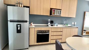 Una cucina moderna con frigorifero integrato, forno, microonde e macchina del caffè sul piano di lavoro.