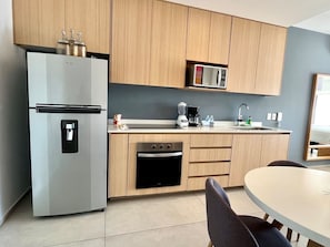 Una cucina moderna con frigorifero integrato, forno, microonde e macchina del caffè sul piano di lavoro.