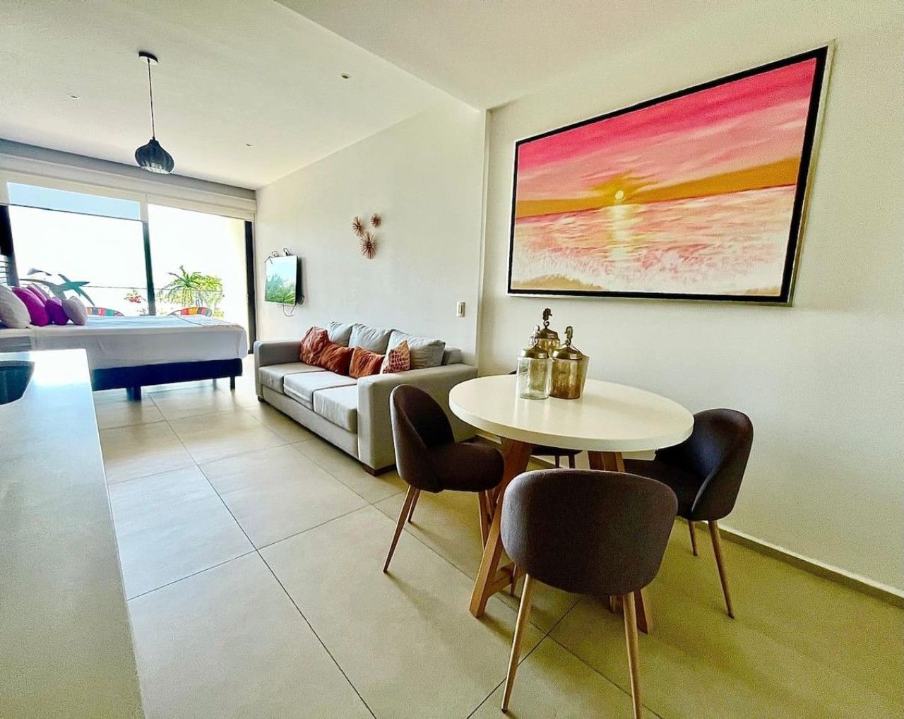 A modern living room with a dining area, a sofa, a TV, and a large painting.