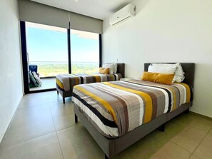 Une chambre moderne avec un grand lit, un plus petit lit et un coin salon.