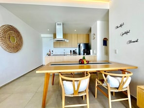 Une cuisine moderne avec des meubles en bois, un réfrigérateur en acier inoxydable et une table à manger avec deux chaises.