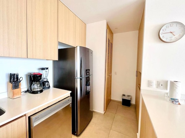Una cocina compacta equipada con refrigerador, cafetera y lavavajillas.