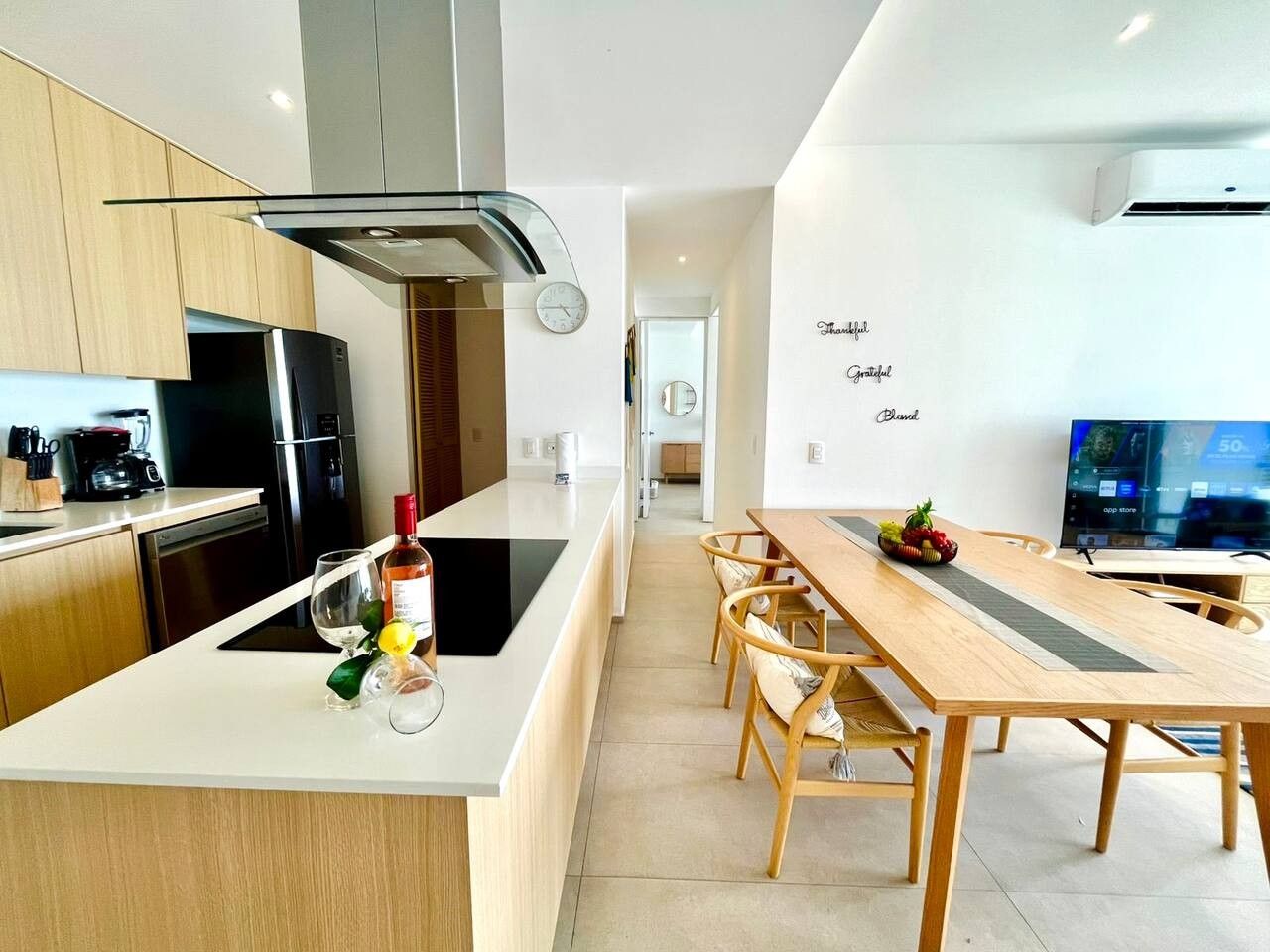 Una cocina moderna con una isla central, armarios de madera y una zona de comedor con una mesa larga y sillas.
