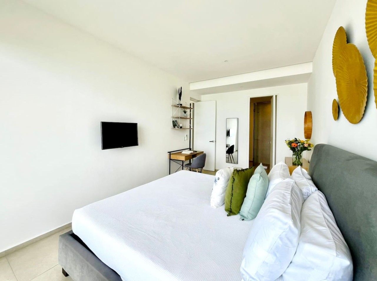 Een moderne hotelkamer met een groot bed, een bureau, een flatscreen televisie en een spiegel.