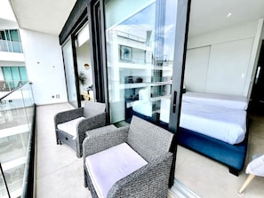 Un balcon doté de meubles en osier, d’un lit et d’une porte vitrée donnant sur un espace extérieur.