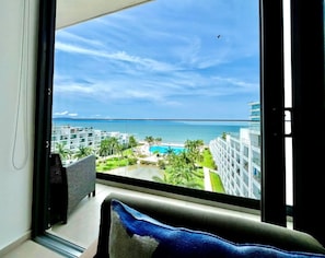 Un balcón con vista a un resort, que incluye una piscina y edificios.