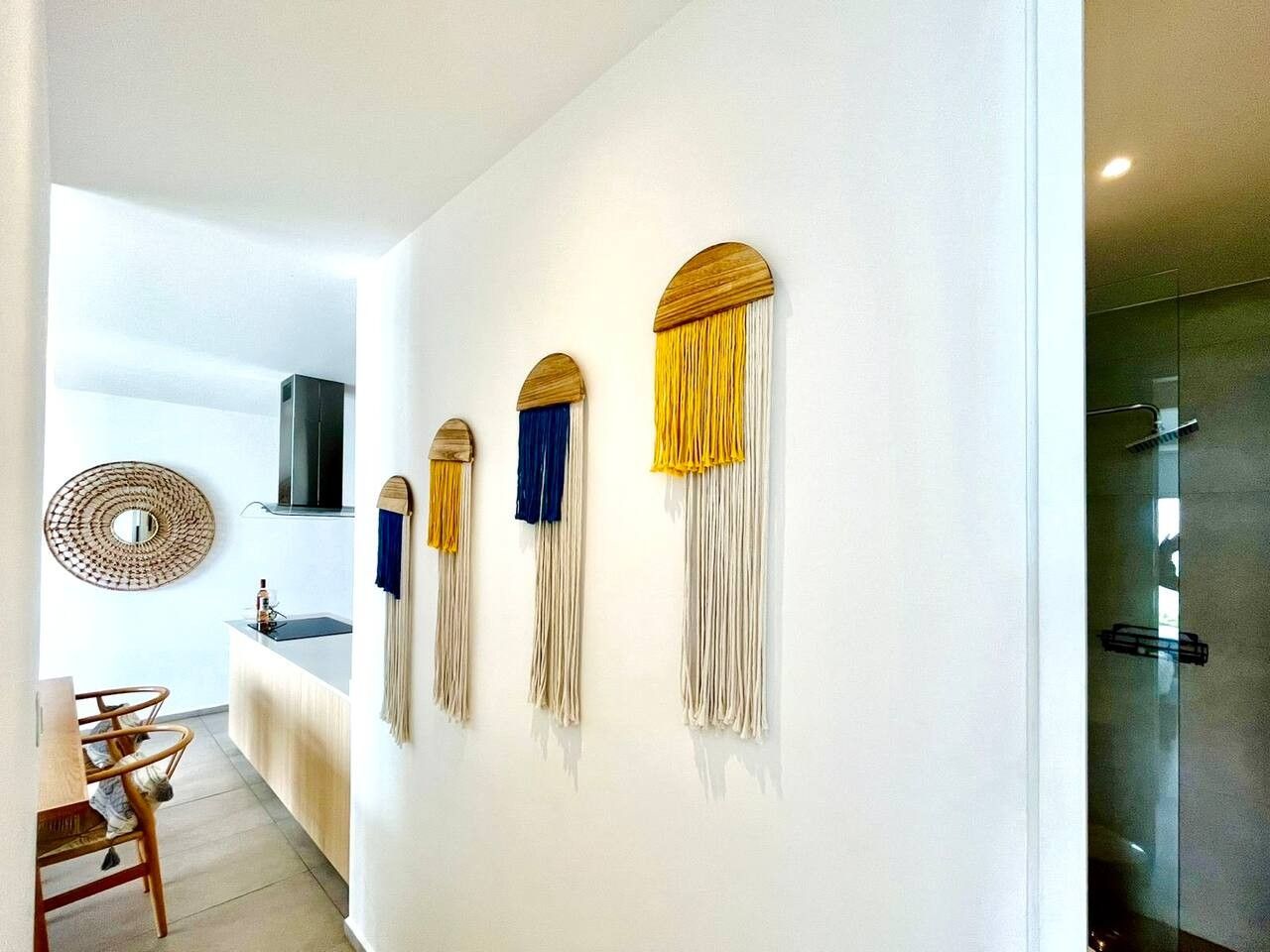 A modern interior with a kitchen area, a dining table, and a wall-mounted decorative piece.