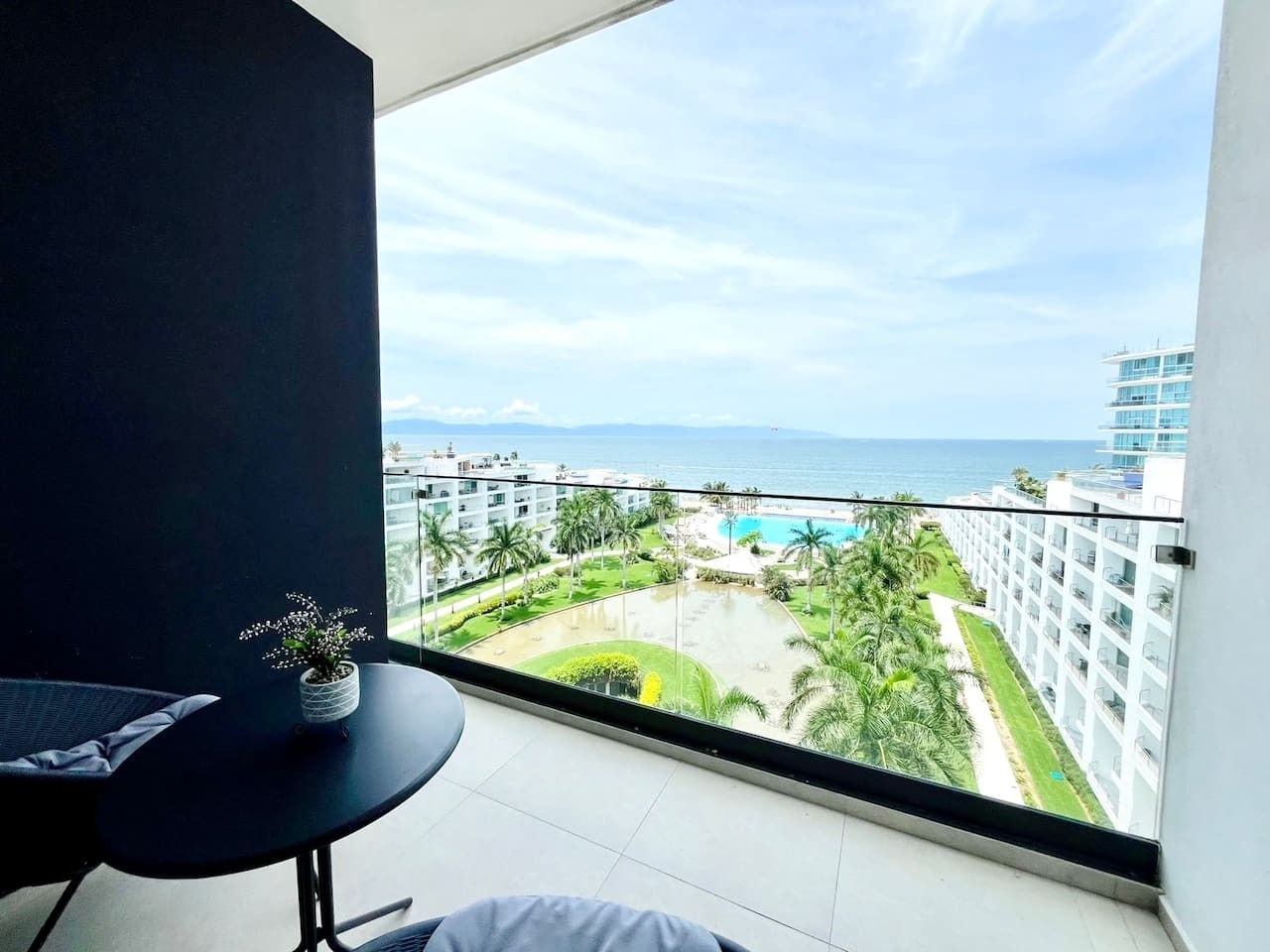 Un balcon avec vue sur une zone de villégiature, comprenant une piscine et des palmiers.
