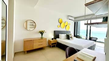 A modern hotel room with a bed, bedside table, and a view of the sea.