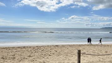 A sandy beach with a wooden post and a rope barrier.