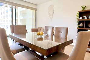 Un'area pranzo moderna con un tavolo in vetro, sedute imbottite e un elemento decorativo a parete.
