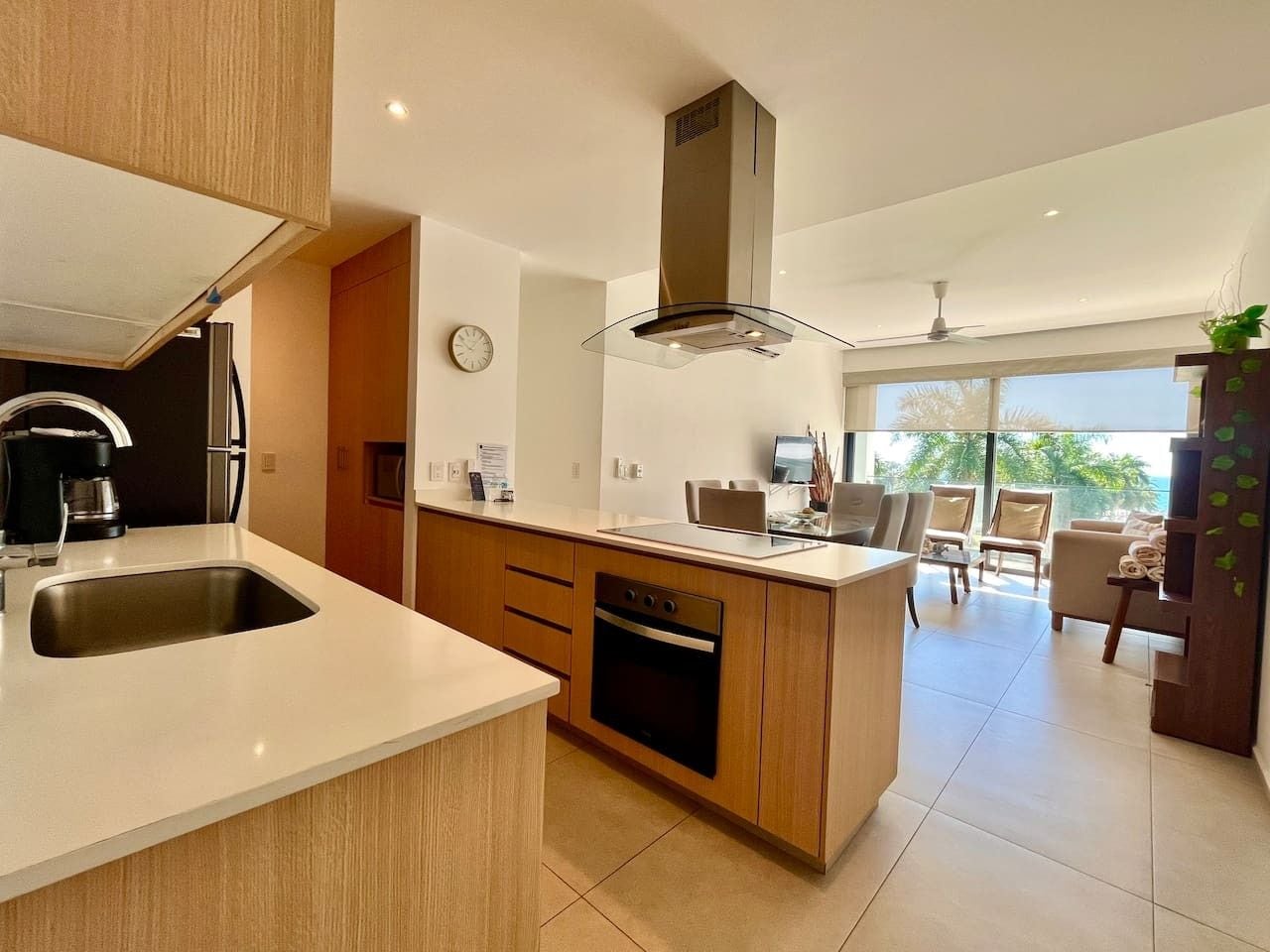 A modern kitchen with a central island, built-in oven, and a large window overlooking a balcony.