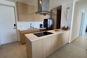 Eine moderne Küche mit einer zentralen Kochinsel, einem eingebauten Ofen und einem Edelstahl-Kühlschrank.