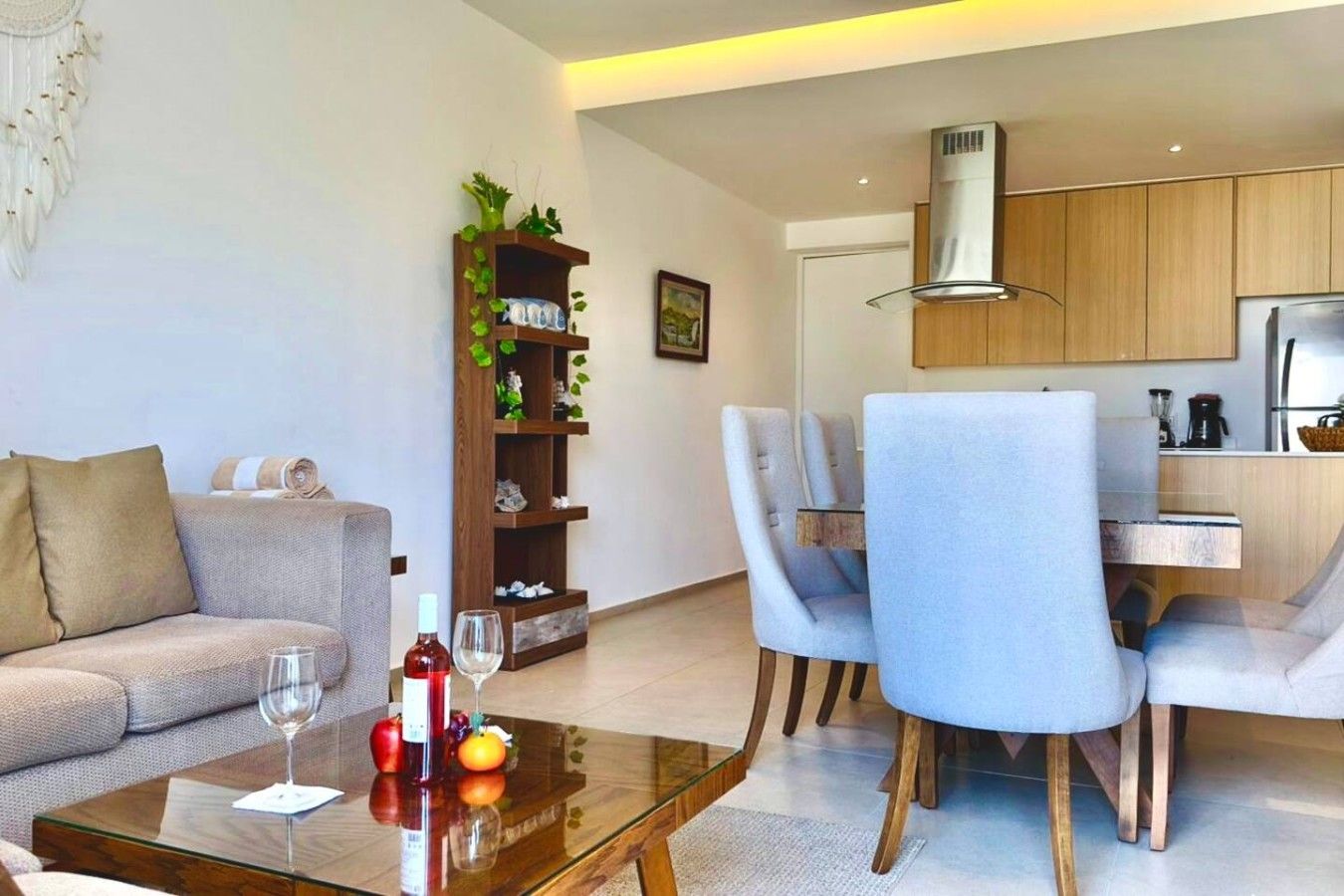 A modern living room with a sofa, a glass coffee table, and a dining area with chairs and a table.